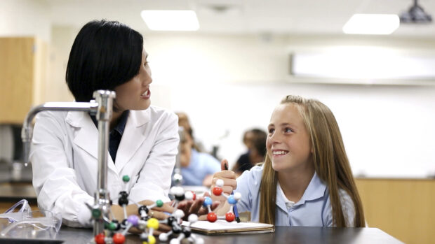 Science teacher helping pupil in lesson