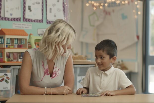 Teacher and pupilreading a book together 