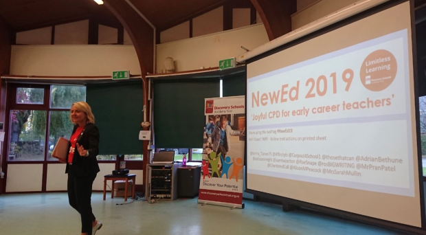 Emma Turner delivering a presentation in front of a powerpoint reading 'NewEd 2019'