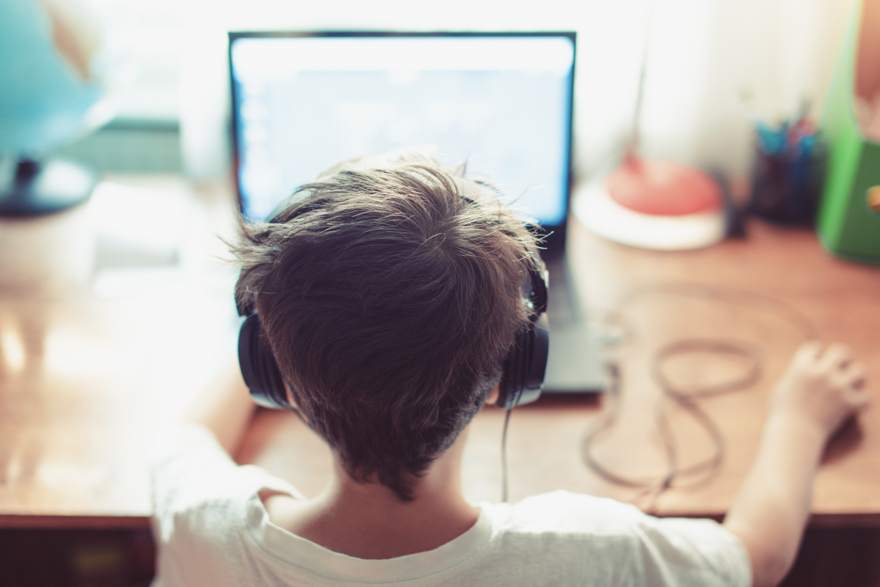 Young boy with headphones working on his laptop