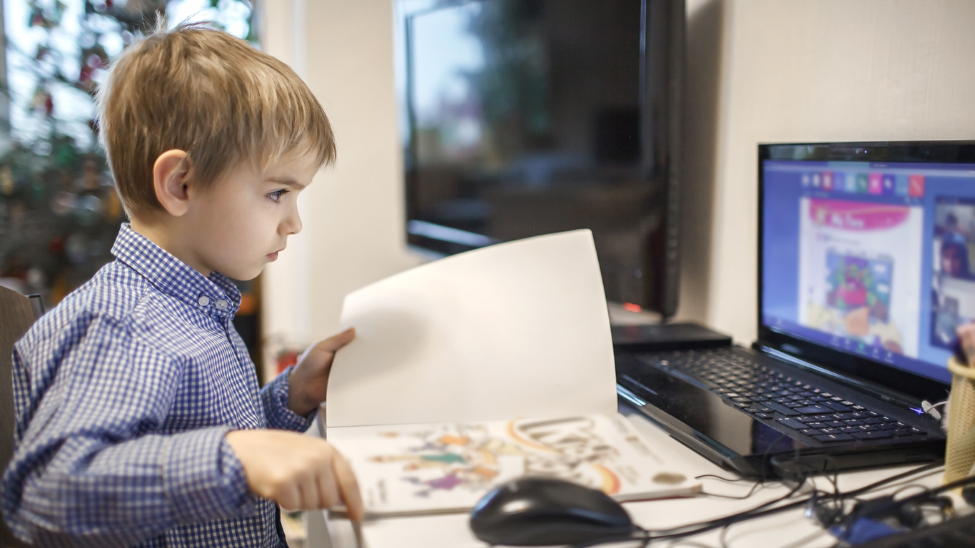 Distant education, online class meeting. Young boy studying during online lesson at home