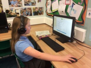 Young girl wearing headphones working at a computer