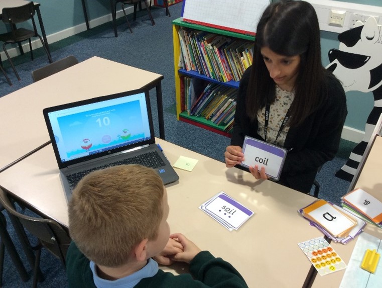 Academic mentor working with a young boy on phonics
