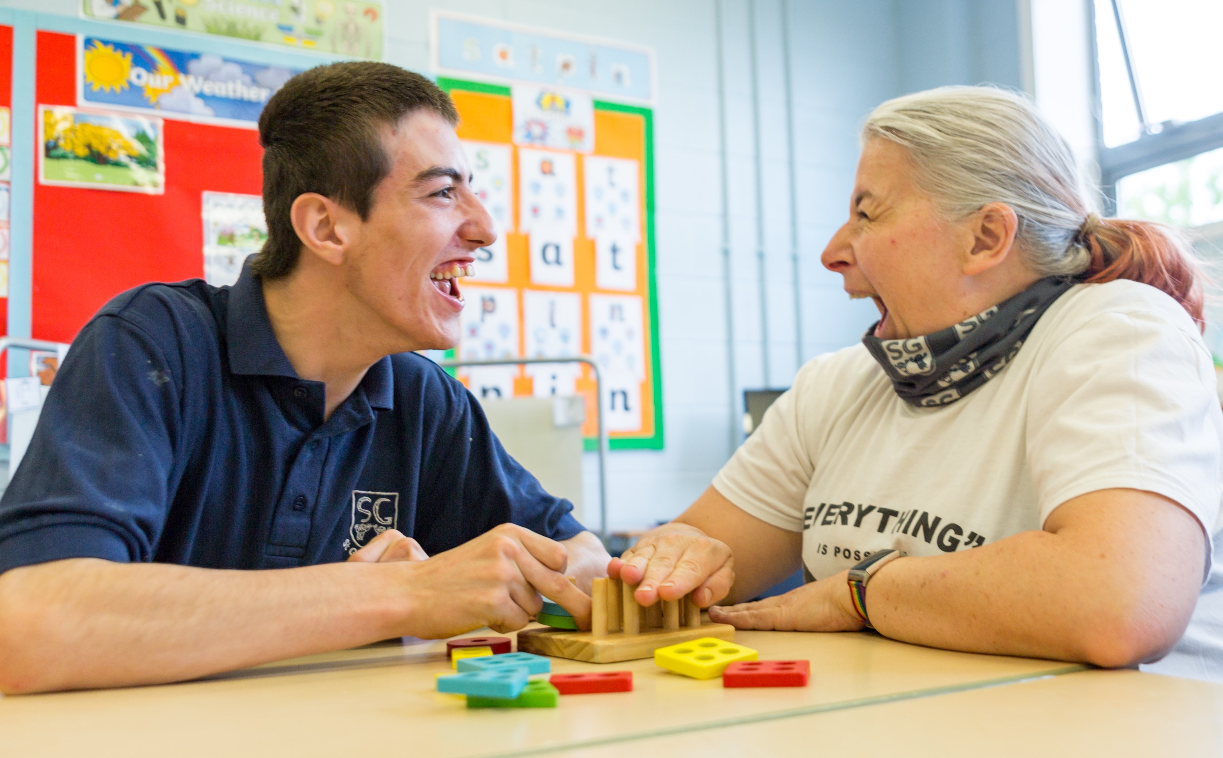 Teenage boy and his Teaching Assistant laughing