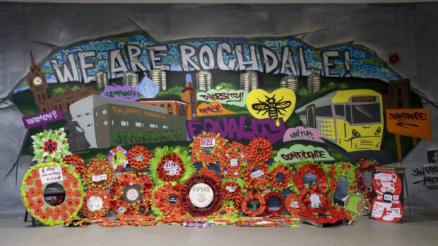 Picture of graffiti wall saying We are Rochdale, with poppies for remembrance at the base