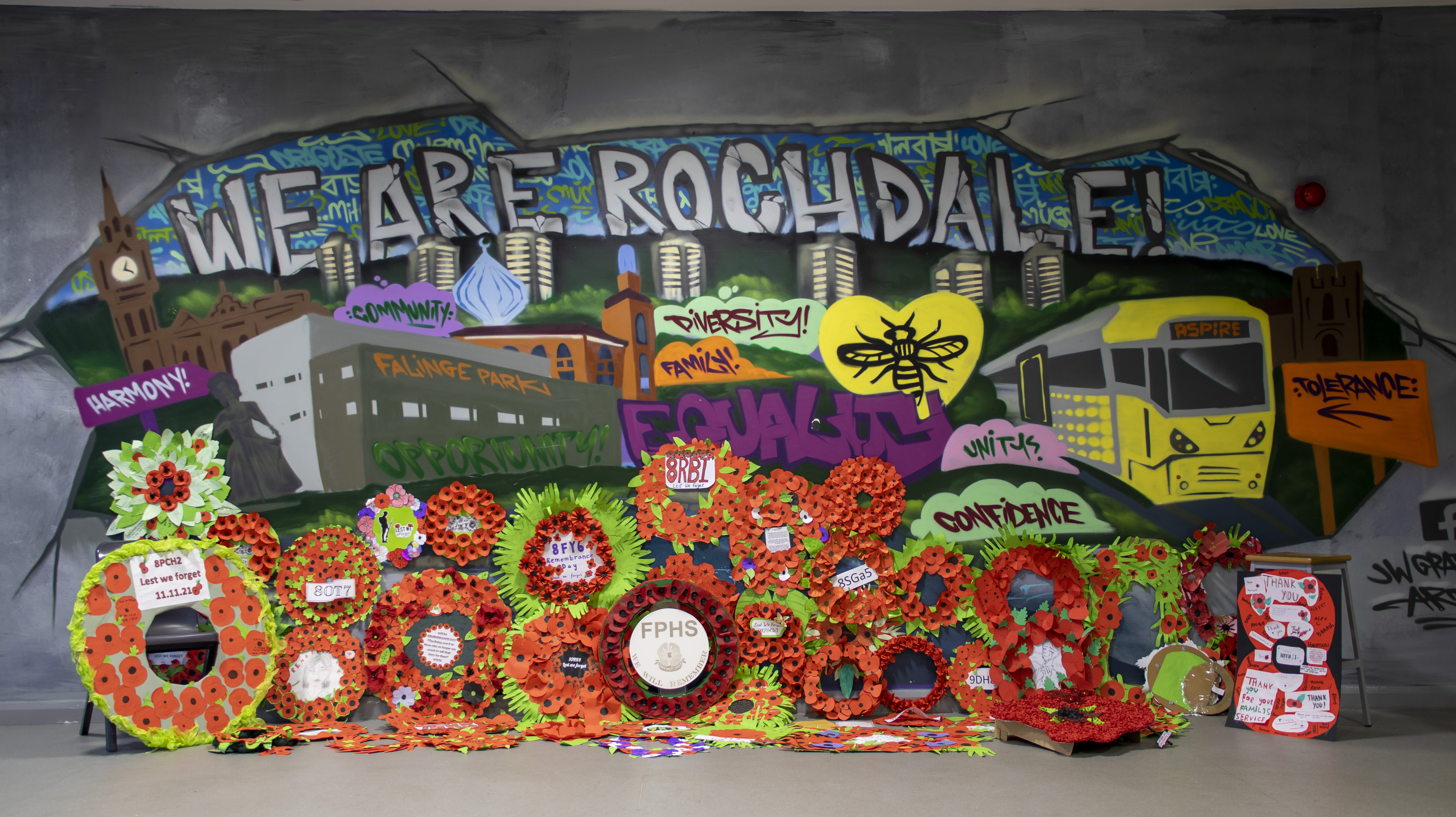 Picture of graffiti wall saying We are Rochdale, with poppies for remembrance at the base