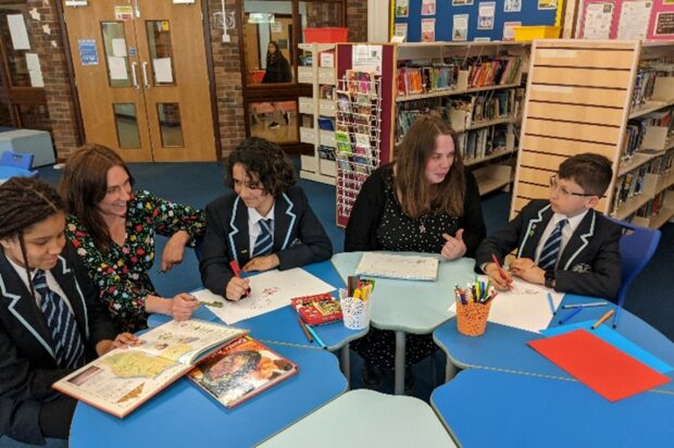 Teachers and pupils at Hove Park sit around a desk in conversation