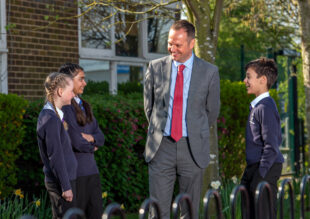 Male teacher talking with pupils outside school