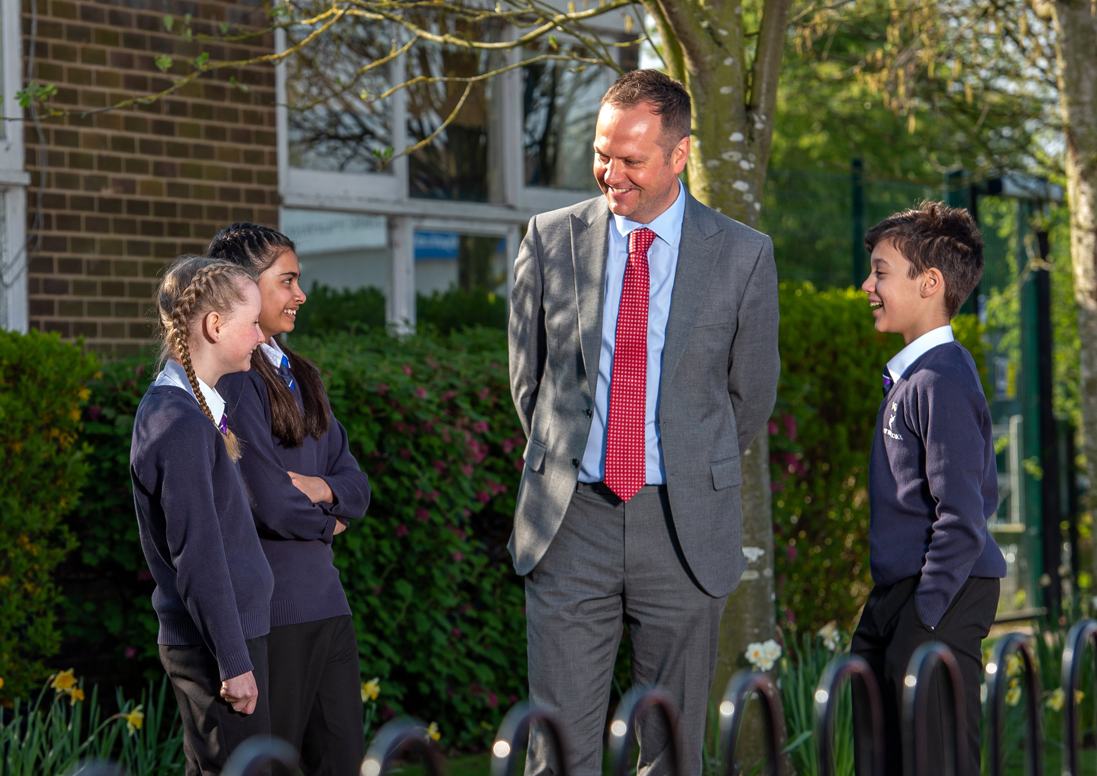 Male teacher talking with pupils outside school