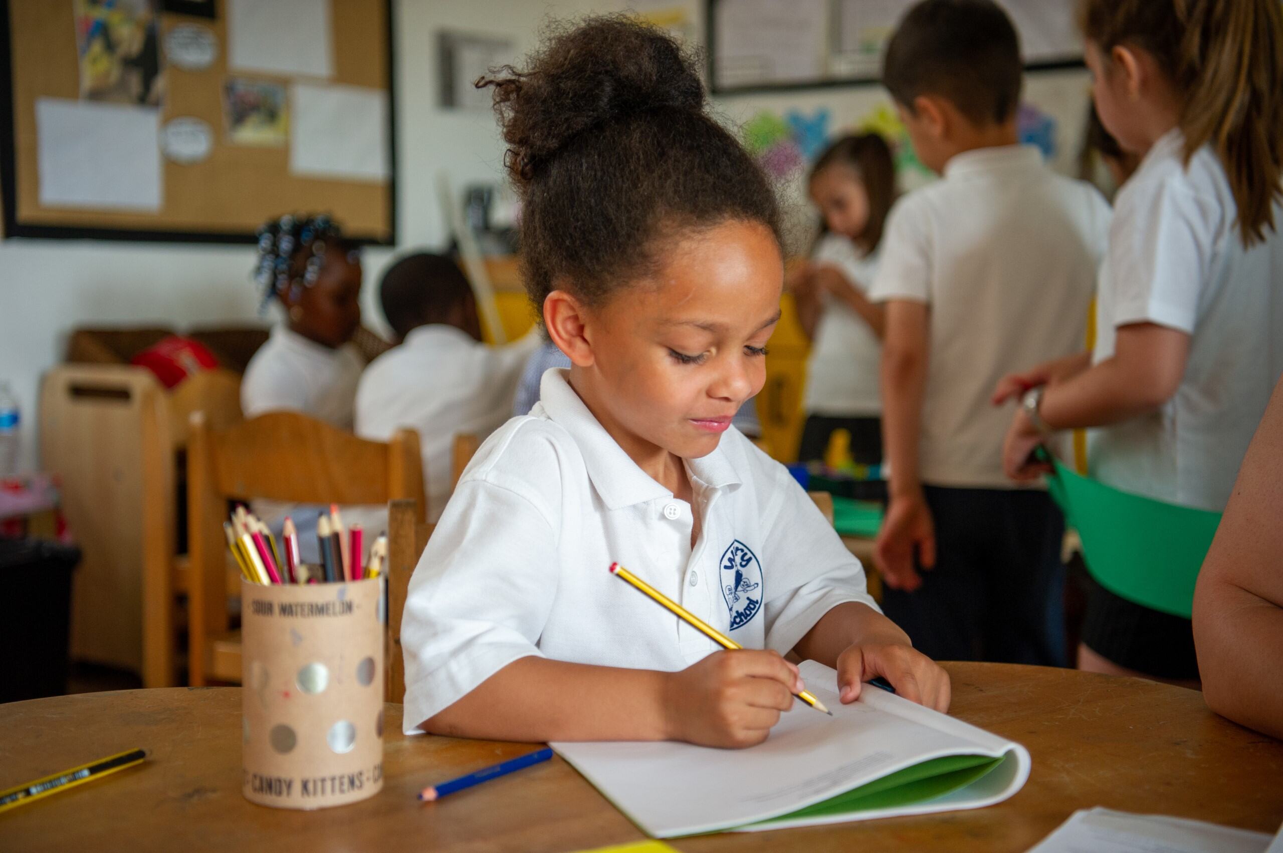 Girl writing in a book in a classroom