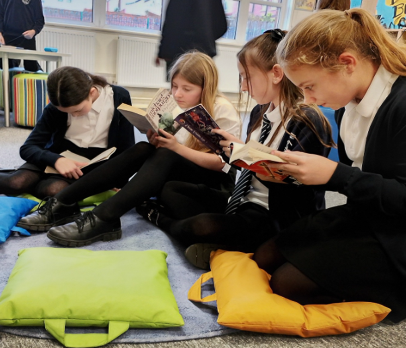 Pupils sitting down reading books
